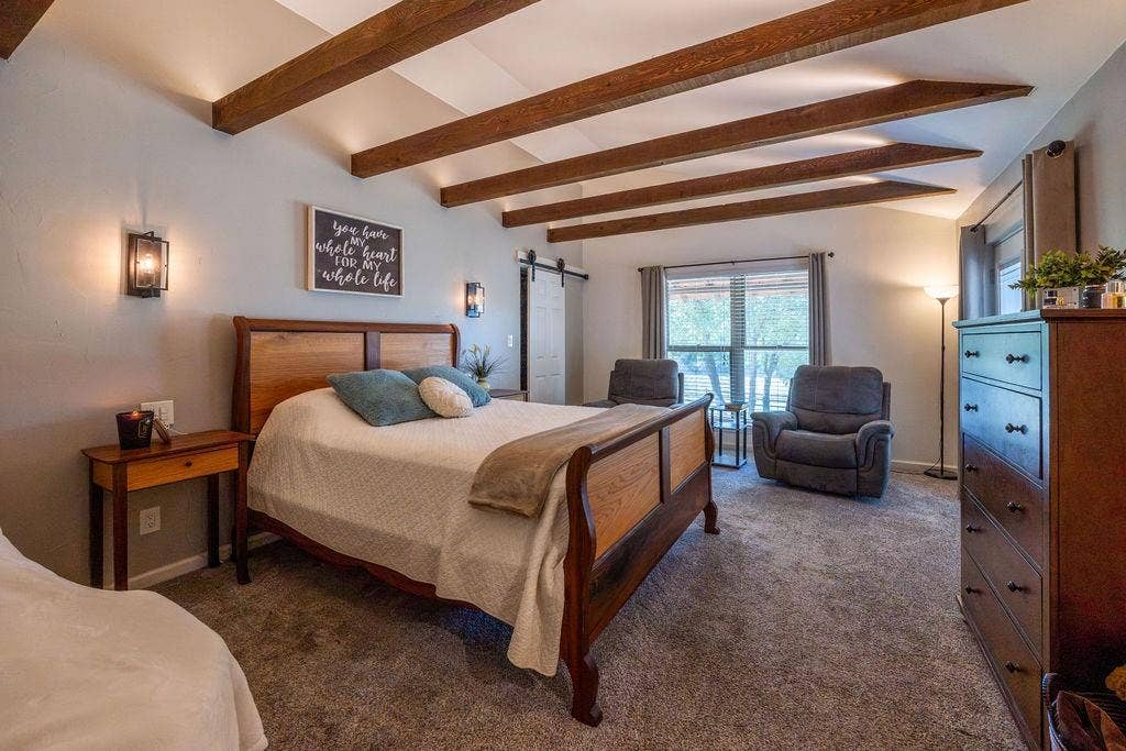384 Fort Graham Road, Waco, TX 76705 Vaulted ceiling with exposed wood beams, wall-mounted sconce lighting, window with exterior scenery, and barn door access