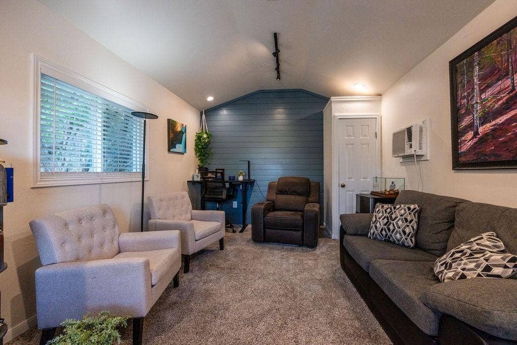 384 Fort Graham Road, Waco, TX 76705 Carpeted living space with a window featuring blinds, track lighting, and a paneled accent wall
