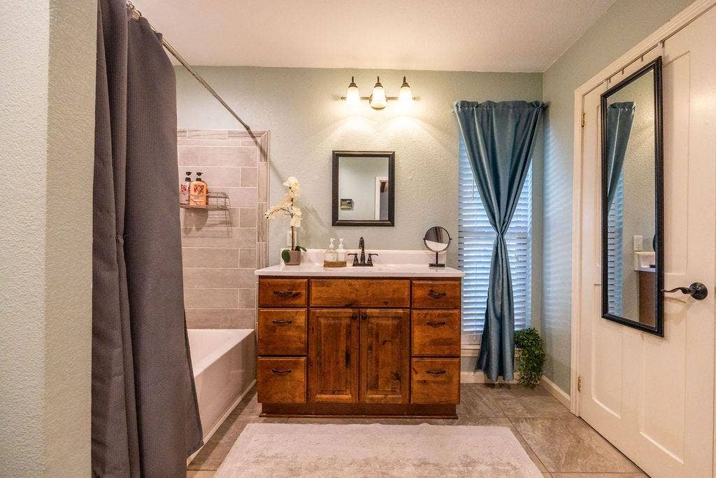 384 Fort Graham Road, Waco, TX 76705 Wood-finish vanity with white countertop, chrome faucet, and rectangular mirror