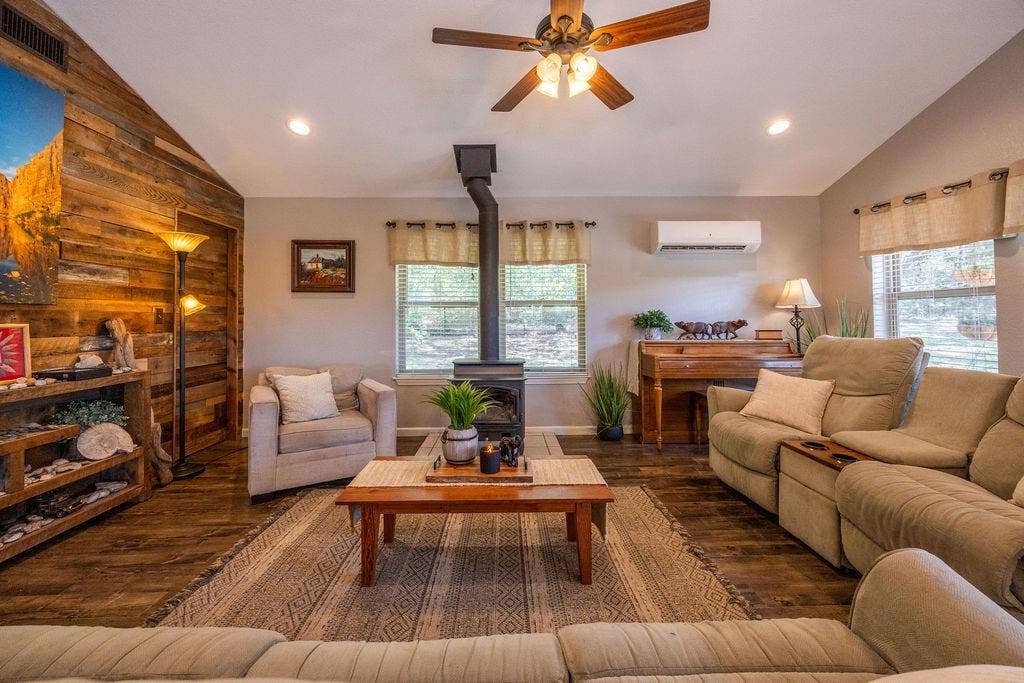384 Fort Graham Road, Waco, TX 76705 Vaulted ceiling, wood-finish flooring, accent wall with wood paneling, freestanding wood-burning stove, and ceiling fan with integrated lighting