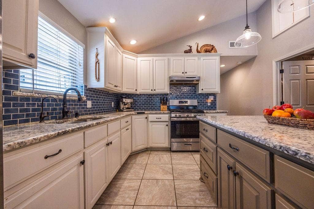 384 Fort Graham Road, Waco, TX 76705 Kitchen featuring white cabinetry, subway tile backsplash, stainless steel appliances, granite countertops, and tile flooring