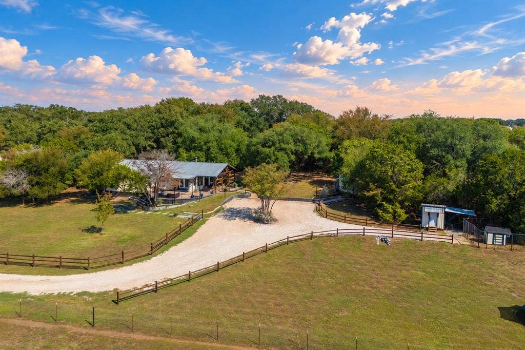384 Fort Graham Road, Waco, TX 76705 Expansive gravel driveway leading to the property, surrounded by a wood-rail fence