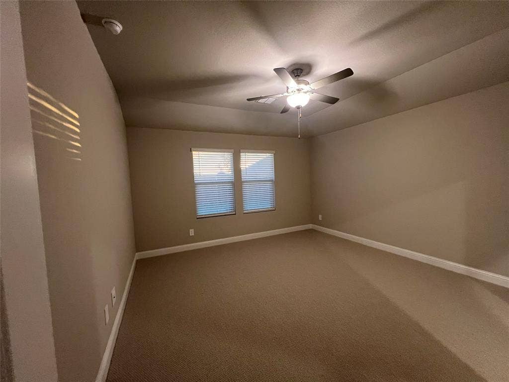Carpeted room featuring a ceiling fan with integrated lighting, two windows with blinds, and neutral painted walls