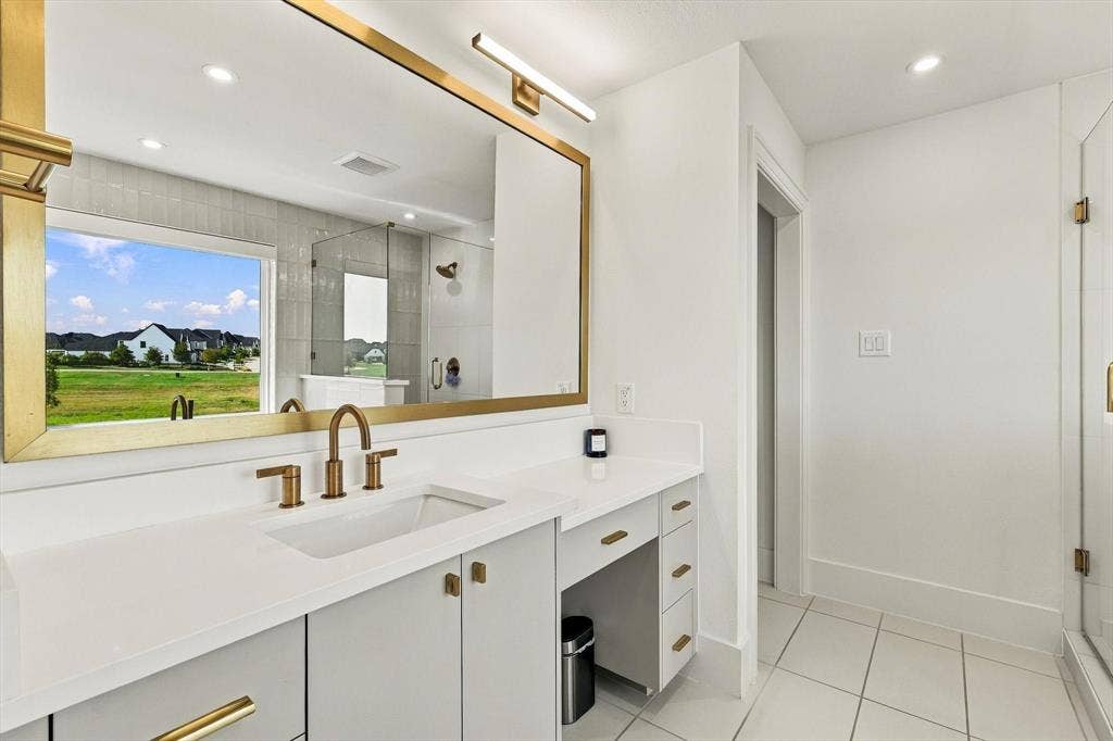 4301 Corabelle Lane, Prosper, TX 75078 Dual-sink vanity with white countertop, brass fixtures, and integrated storage
