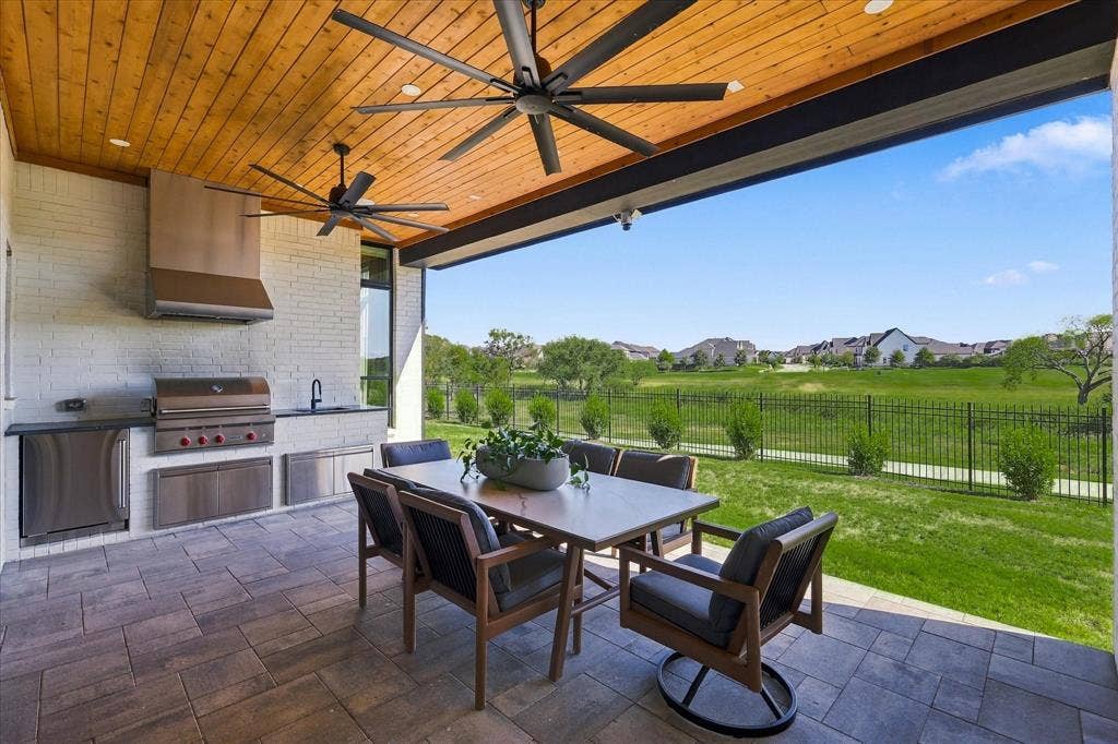 4301 Corabelle Lane, Prosper, TX 75078 Covered outdoor living space featuring an outdoor kitchen with built-in grill, stainless steel appliances, a wood-paneled ceiling, and large ceiling fans