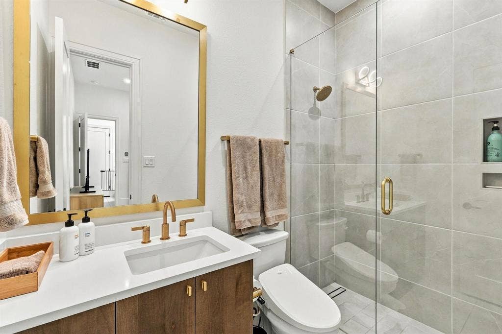 4301 Corabelle Lane, Prosper, TX 75078 Wood-finish vanity with a white countertop and gold-tone fixtures