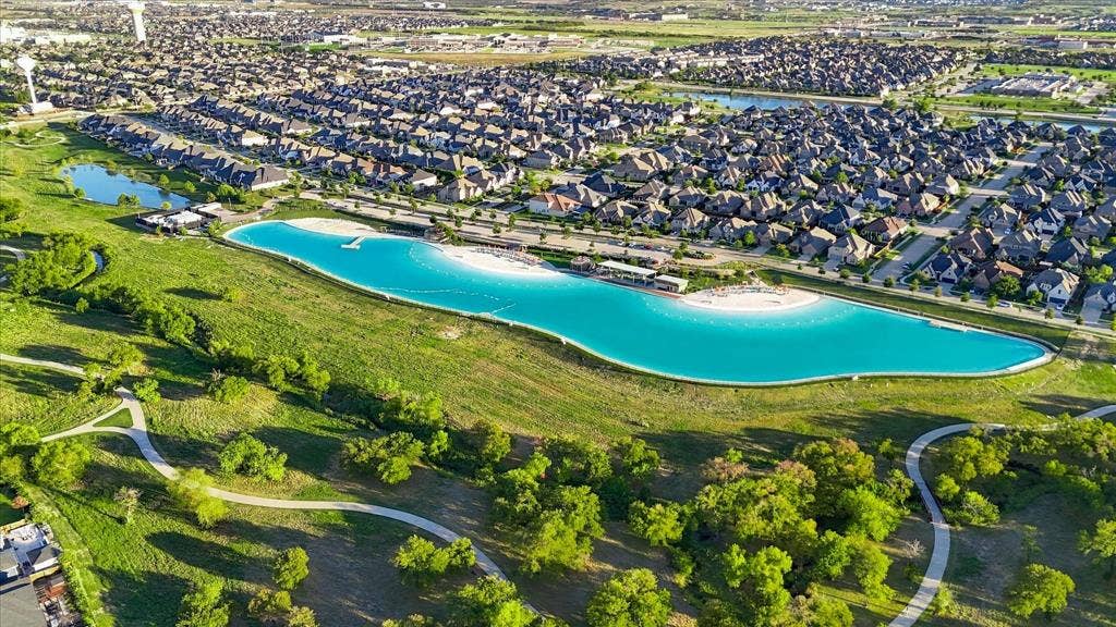 4301 Corabelle Lane, Prosper, TX 75078 Expansive residential development featuring a large lagoon with a white sand beach, paved walking paths, and abundant green spaces
