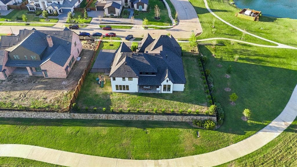 4301 Corabelle Lane, Prosper, TX 75078 White exterior with dark roof, integrated garage, and a retaining wall with landscaping
