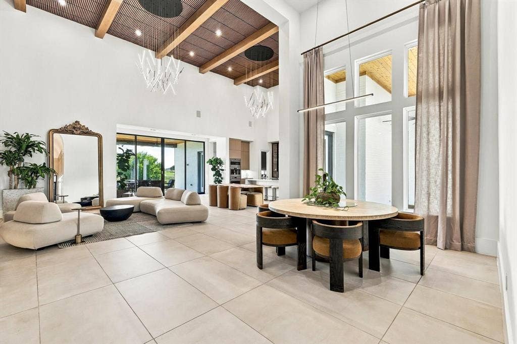4301 Corabelle Lane, Prosper, TX 75078 Vaulted ceilings with exposed beams, large format floor tiling, expansive window wall, linear lighting fixture, and a sliding glass door