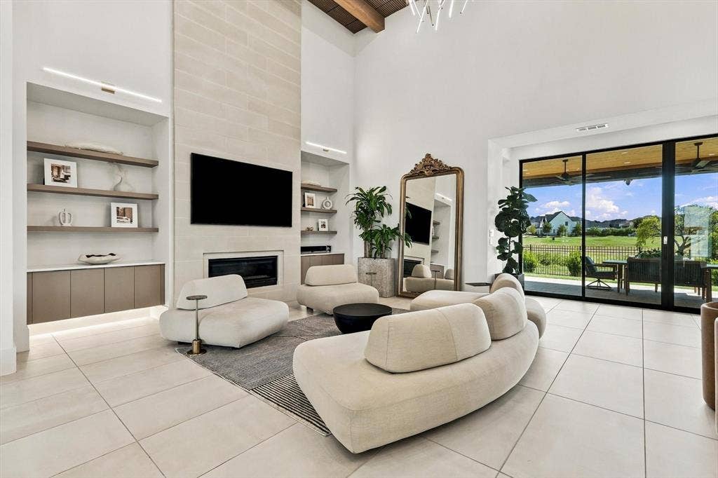 4301 Corabelle Lane, Prosper, TX 75078 Vaulted ceiling, stone-clad fireplace, built-in shelving, integrated cabinetry, and large sliding glass doors