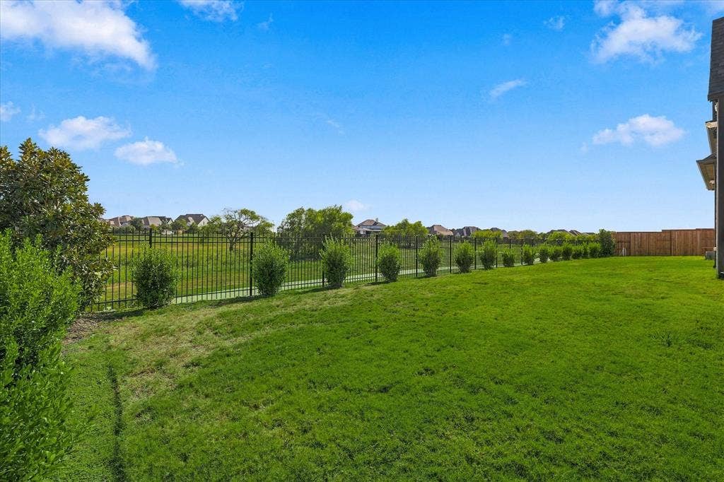4301 Corabelle Lane, Prosper, TX 75078 Expansive backyard featuring a manicured lawn, established landscaping, and a dark metal fence