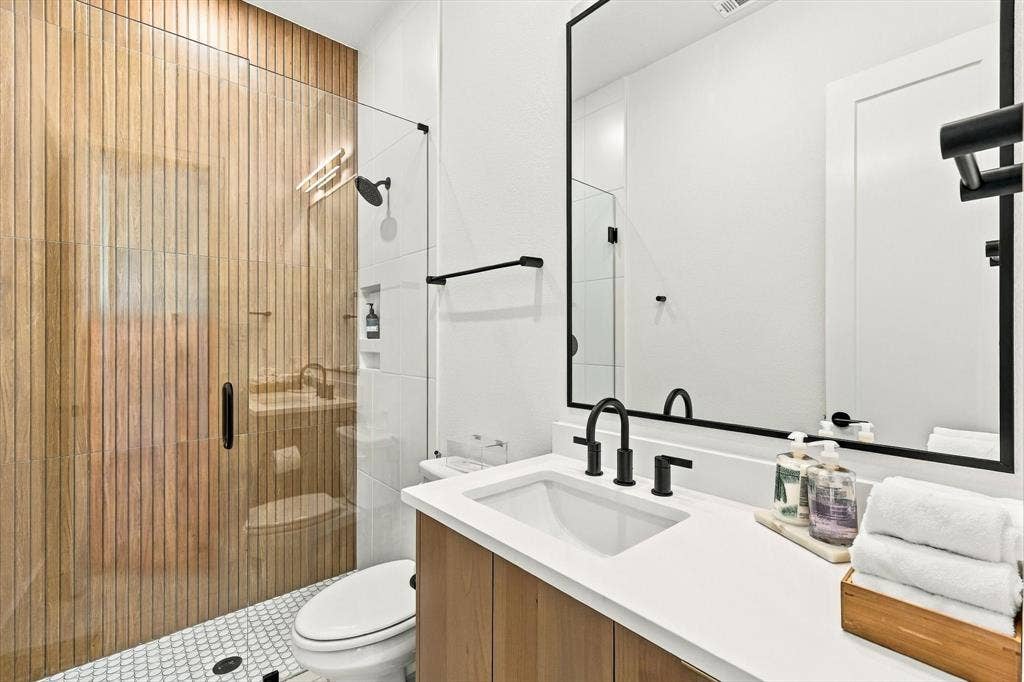 4301 Corabelle Lane, Prosper, TX 75078 Walk-in shower with wood-finish tile surround, glass enclosure, and recessed shelving