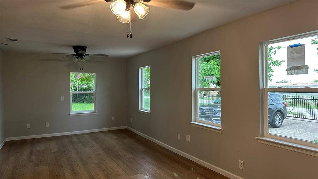 Wood-finish flooring, neutral wall paint, white trim, and multiple windows