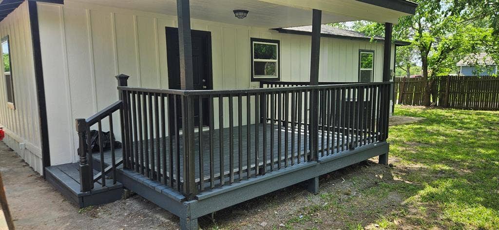 Expansive covered deck with dark railings, exterior lighting, and a board and batten facade