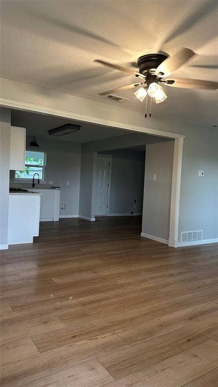 Wood-finish flooring throughout, white trim, and a ceiling fan with integrated lighting