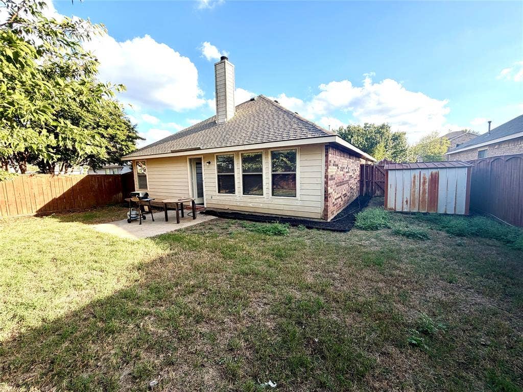 9016 Warren Drive, McKinney, TX 75071 Rear exterior featuring horizontal lap siding, a masonry chimney, a concrete patio, and a fenced backyard with an exterior storage structure