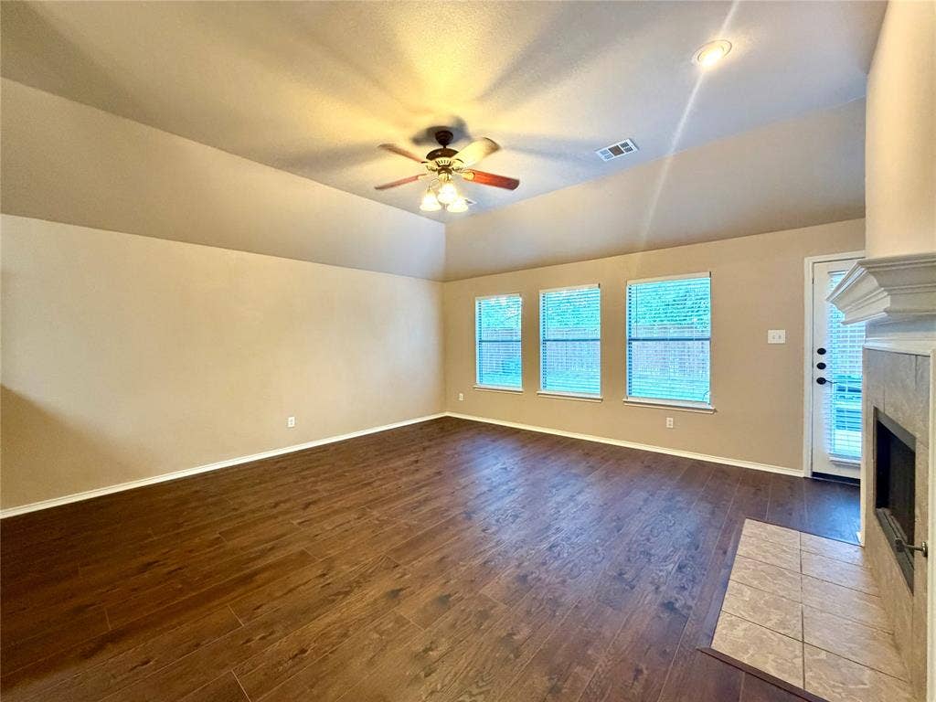 9016 Warren Drive, McKinney, TX 75071 Vaulted ceiling, wood-finish flooring, recessed lighting, ceiling fan with light kit, and a stone-surround fireplace with a mantel