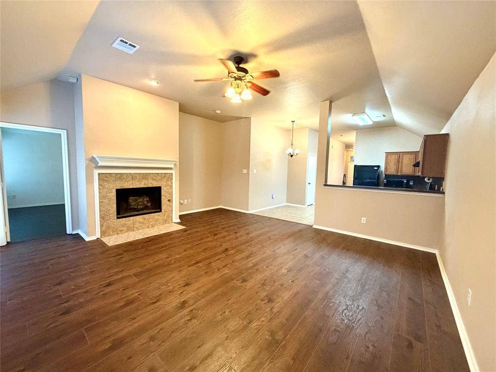 9016 Warren Drive, McKinney, TX 75071 Living area featuring wood-finish flooring, a vaulted ceiling, a fireplace with a tile surround and mantel, and a ceiling fan