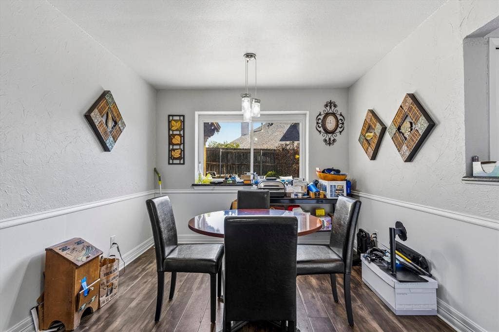 Wood-finish flooring with white baseboards and chair rail molding