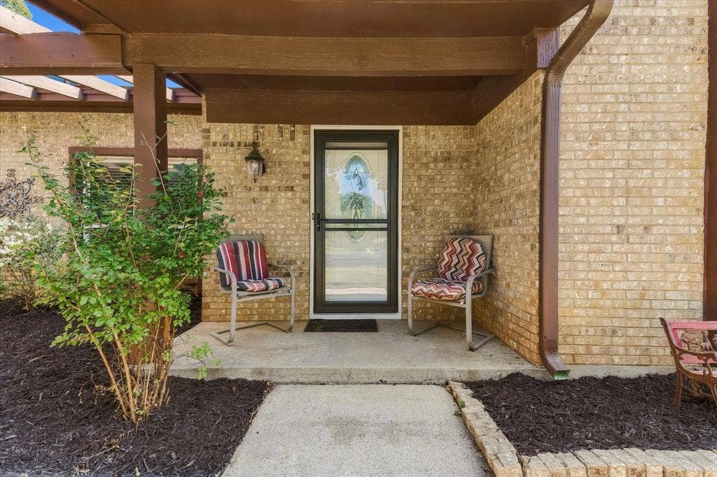 Brick exterior with covered entry, storm door, and exterior lighting