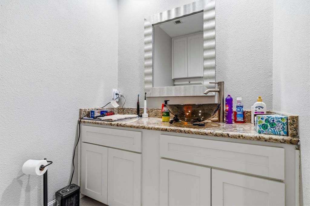 Vanity with granite countertop, vessel sink, brushed nickel faucet, and white shaker-style cabinetry