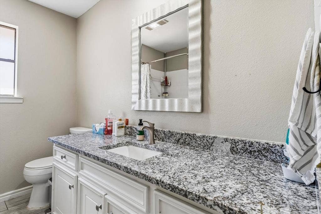 Vanity with a granite countertop, undermount sink, and a framed mirror