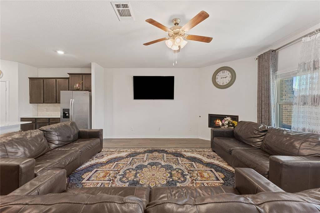 Wood-finish flooring, ceiling fan with integrated lighting, recessed lighting, and a built-in fireplace