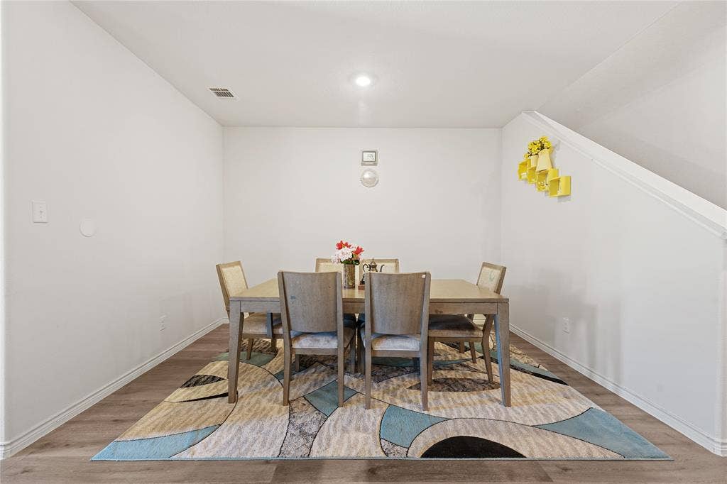 Wood-finish flooring with white baseboards, recessed ceiling lighting, and a sloped ceiling detail