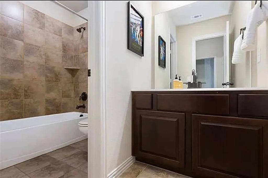 Full bathroom featuring toilet, tiled shower / bath combo, and vanity