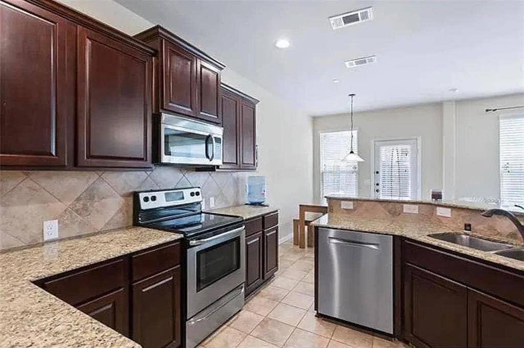 Kitchen featuring decorative light fixtures, decorative backsplash, sink, appliances with stainless steel finishes, and light tile patterned floors