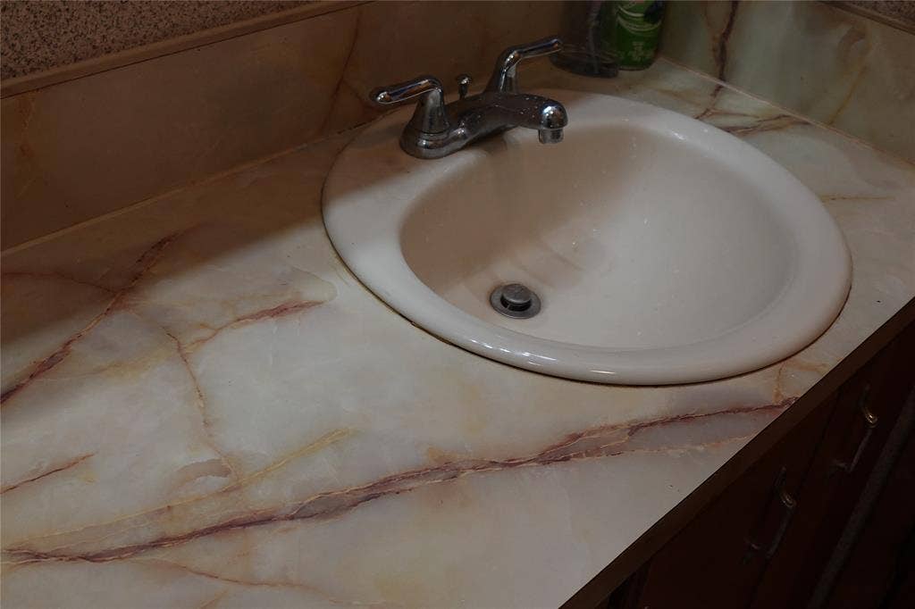 Vanity with an integrated oval sink and chrome faucet, featuring a marbled countertop with an integrated backsplash