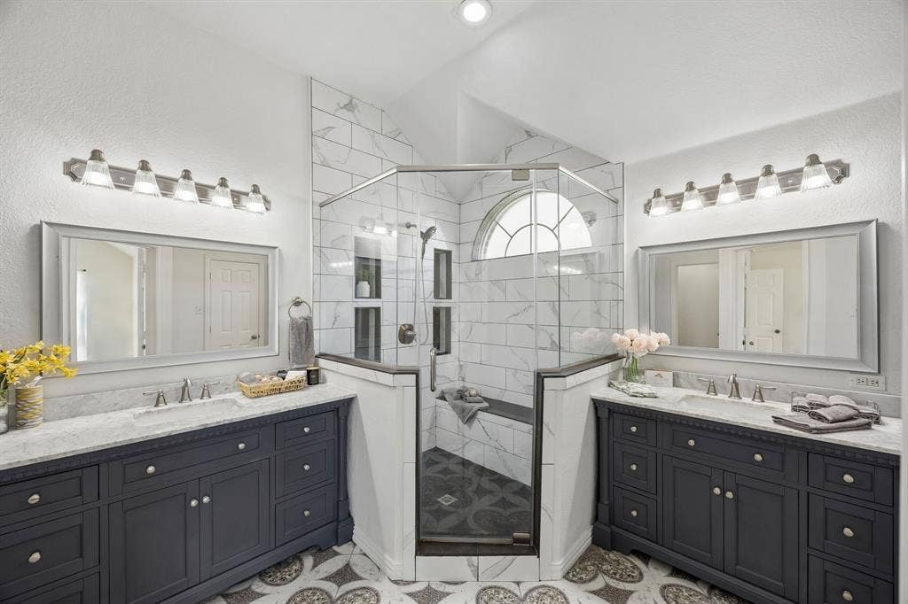 This beautifully designed bathroom features two spacious vanities, stylish finishes and an impressive glass-enclosed walk-in shower with seating!