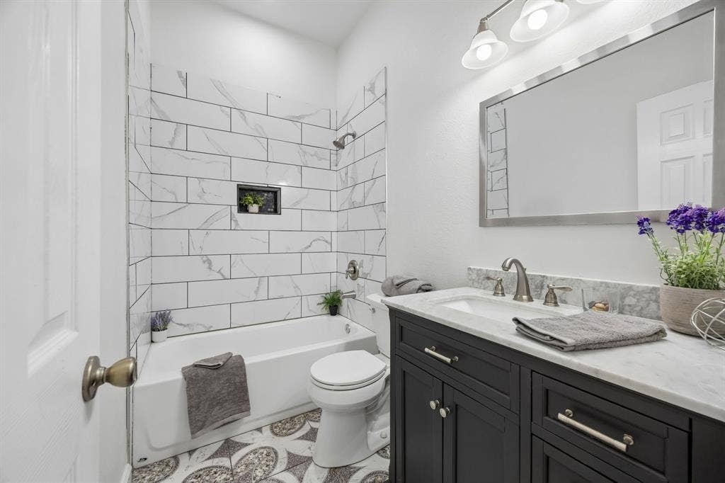 This Guest bath enjoys a combination of sophisticated cabinetry, elegant mirror and lighting, and a relaxing tub-shower combination.