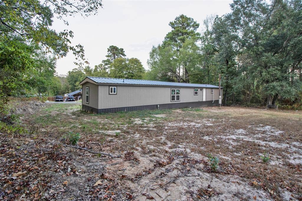 Manufactured home with neutral tone siding, dark trim, and a metal roof
