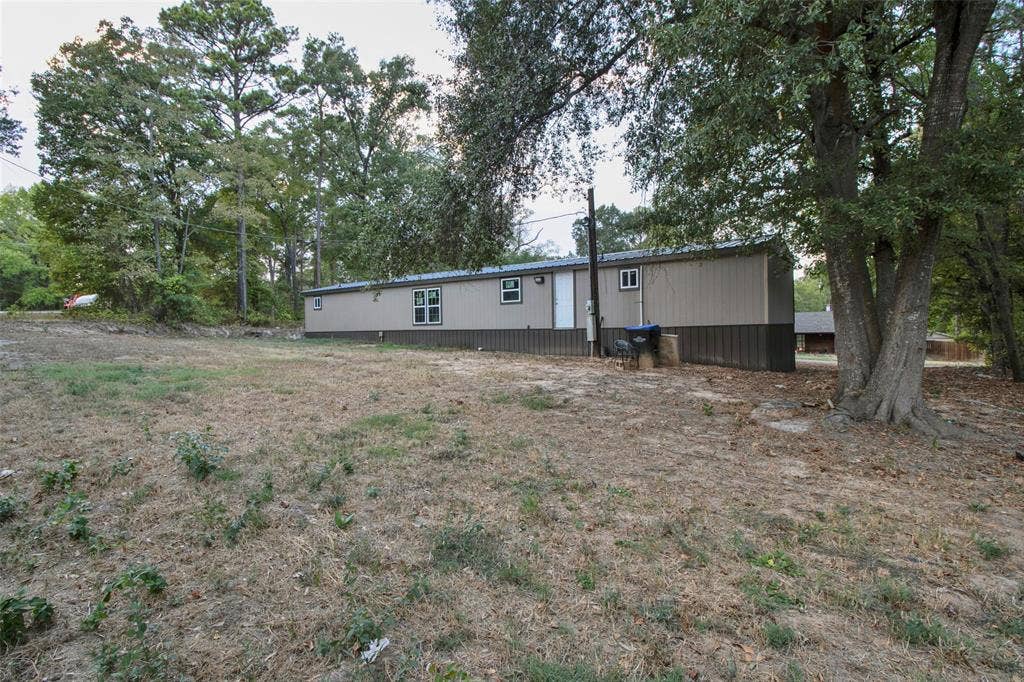 Spacious property with mature trees, a two-tone exterior, and multiple windows
