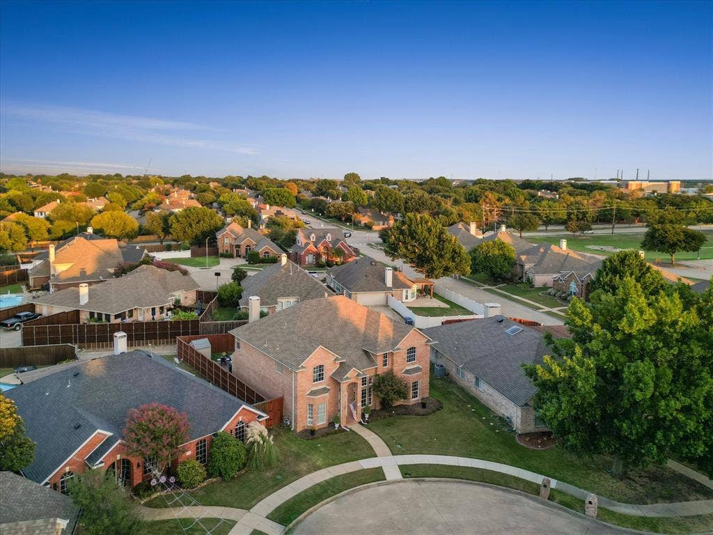 3303 Felicia Court, McKinney, TX 75070 Aerial perspective of a multi-story brick residence featuring a multi-gabled roofline, concrete driveway, and established landscaping