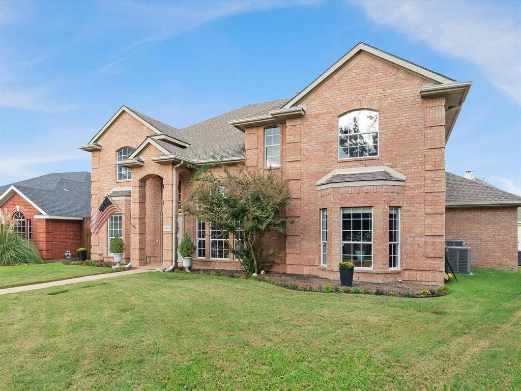 3303 Felicia Court, McKinney, TX 75070 Multi-level brick exterior featuring a covered entryway, multi-pane windows, arched detailing, and a shingled roof