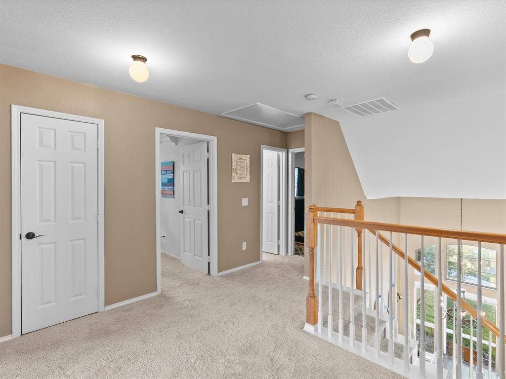 3303 Felicia Court, McKinney, TX 75070 Hallway featuring wall-to-wall carpeting, white six-panel interior doors, and a wood-finish staircase railing with vertical balusters