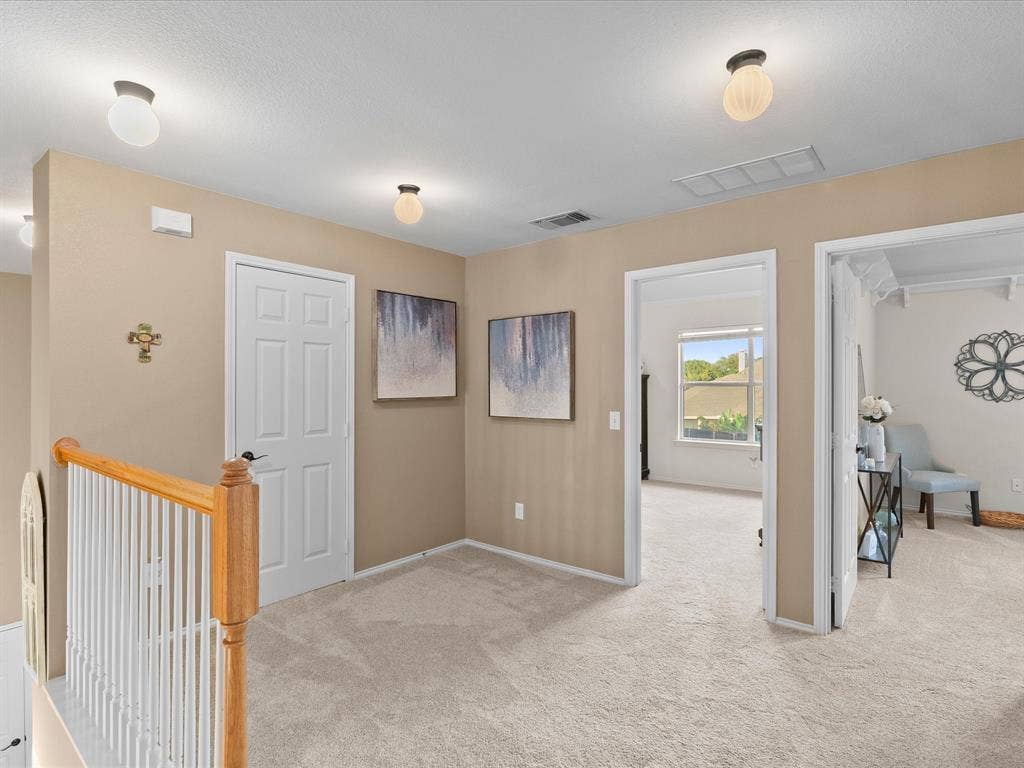3303 Felicia Court, McKinney, TX 75070 Neutral-toned interior landing featuring carpeted flooring, a wooden handrail with vertical spindles, and multiple semi-flush mount light fixtures