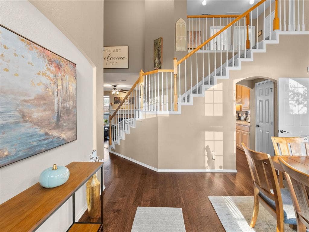 3303 Felicia Court, McKinney, TX 75070 Entryway featuring high ceilings, wood-finish flooring, and a staircase with white balusters and wood-finish handrails