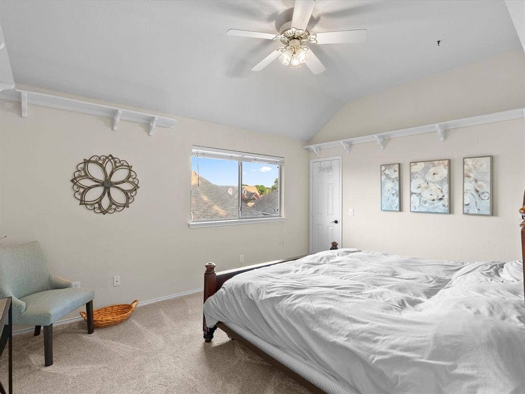 3303 Felicia Court, McKinney, TX 75070 Vaulted ceiling featuring a central multi-blade ceiling fan with integrated light fixture, carpeted flooring, and decorative wall-mounted shelving