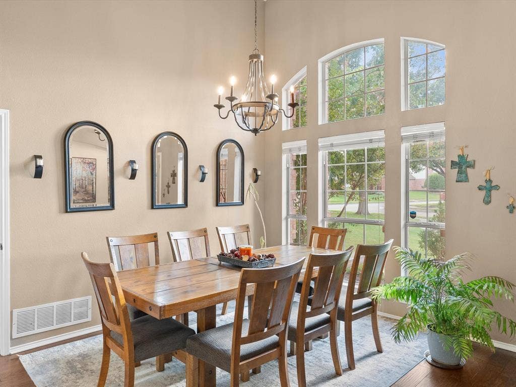 3303 Felicia Court, McKinney, TX 75070 High ceilings with a multi-light wood and metal chandelier, expansive arched windows, and wall-mounted sconce lighting