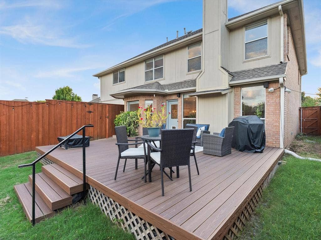 3303 Felicia Court, McKinney, TX 75070 Multi-level wood-finish deck featuring a matte black metal handrail and lattice skirting, complemented by a brick and siding exterior with a prominent chimney