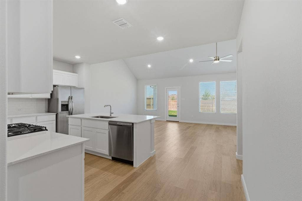 637 Sierra Ridge, Lavon, TX 75166 Modern kitchen featuring white cabinetry, stainless steel appliances, an island with an integrated sink, and light wood-finish flooring