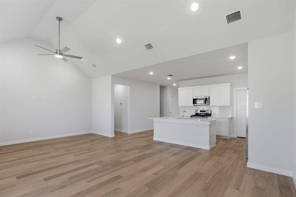 637 Sierra Ridge, Lavon, TX 75166 Vaulted ceiling with a ceiling fan, recessed lighting, wood-finish flooring, white kitchen cabinetry, and stainless steel appliances