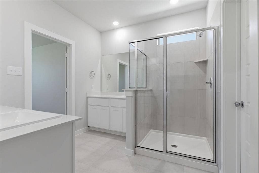 637 Sierra Ridge, Lavon, TX 75166 Spacious bathroom featuring a built-in bathtub, a walk-in shower with clear glass enclosure, and a vanity with a white countertop