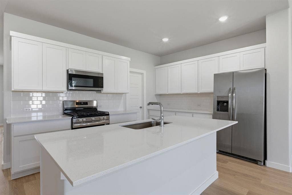 637 Sierra Ridge, Lavon, TX 75166 Kitchen featuring white shaker cabinetry, white subway tile backsplash, stainless steel appliances, and a central island with a sink and a gooseneck faucet