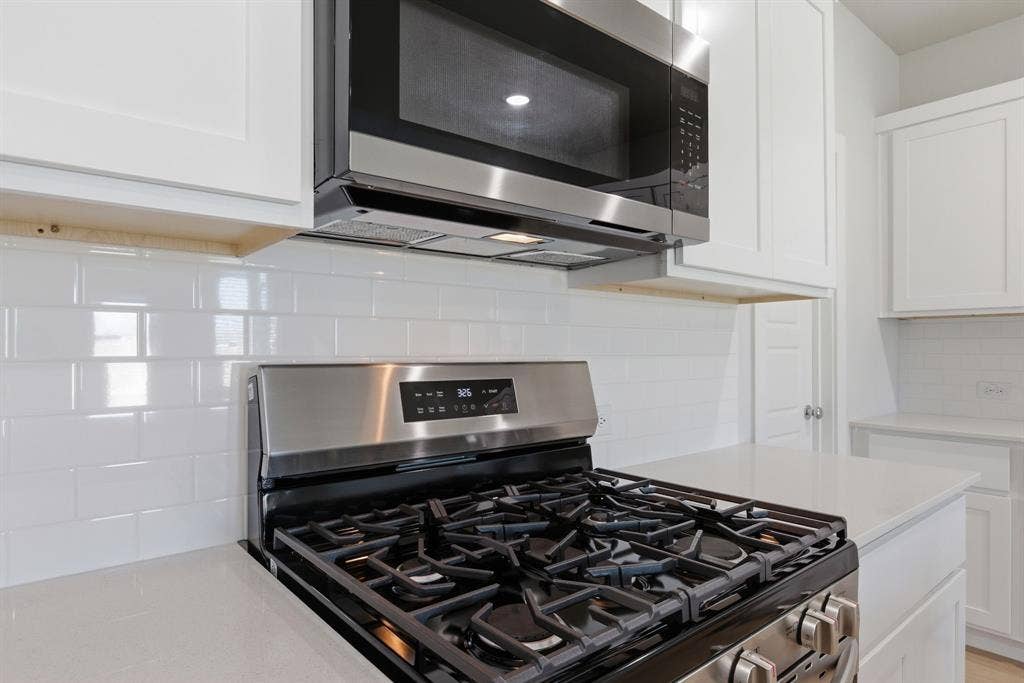 637 Sierra Ridge, Lavon, TX 75166 Stainless steel gas range with a matching microwave, white subway tile backsplash, white shaker-style cabinetry, and light-toned countertops
