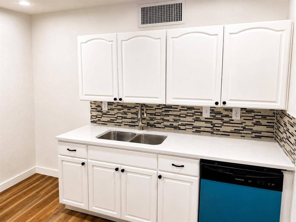 542 Hanover Drive, Allen, TX 75002 Kitchenette featuring white cabinetry with black hardware, a mosaic tile backsplash, double basin stainless steel sink, and light-toned countertops