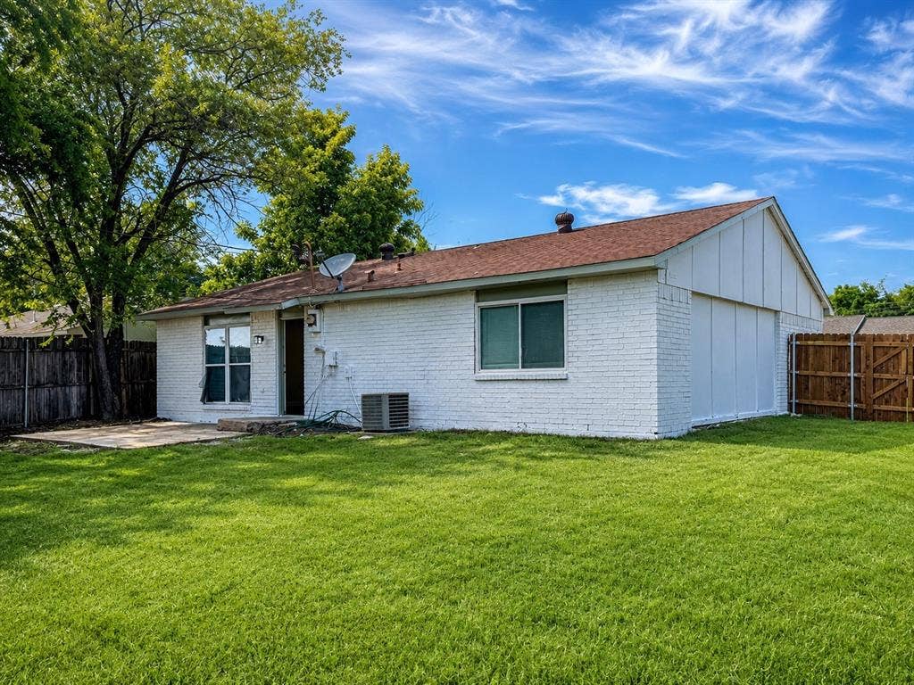 542 Hanover Drive, Allen, TX 75002 Expansive backyard featuring a manicured lawn, white brick exterior, a concrete patio, and a wood privacy fence